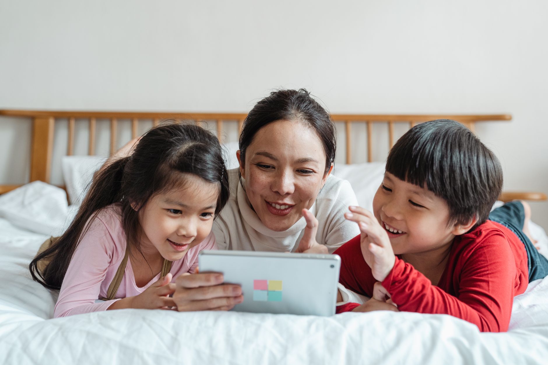 Mama z dwójką dzieci na łóżku bawiąca się tabletem Mama z dwójką dzieci na łóżku bawiąca się tabletem
