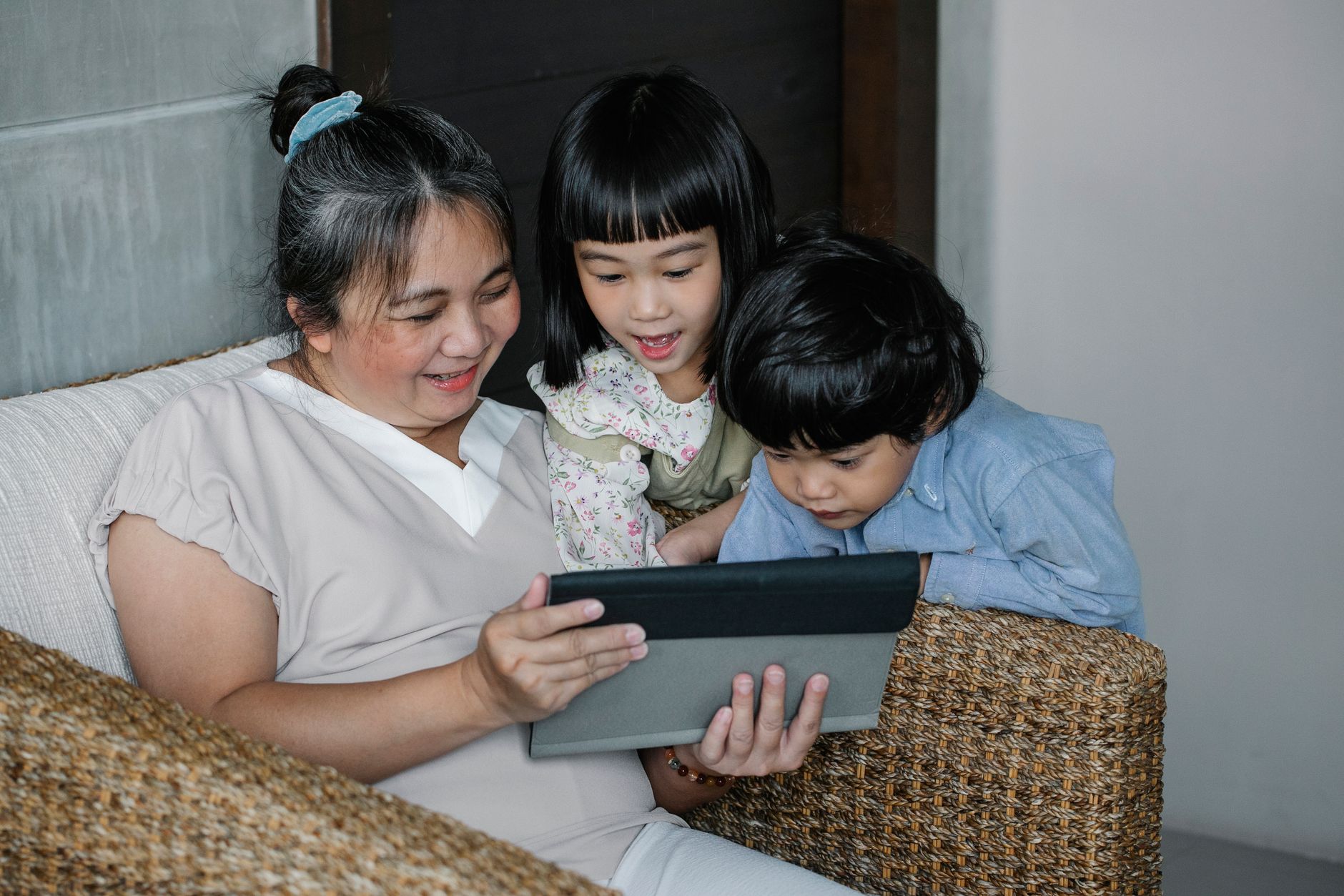 Opiekunka i dzieci oglądają tablet w przytulnym domowym salonie